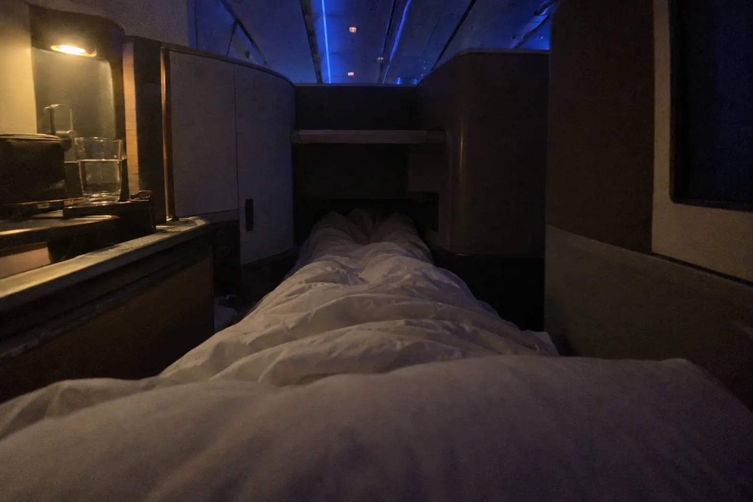 View from a business class bed on the same night flight: legs stretched flat under a duvet